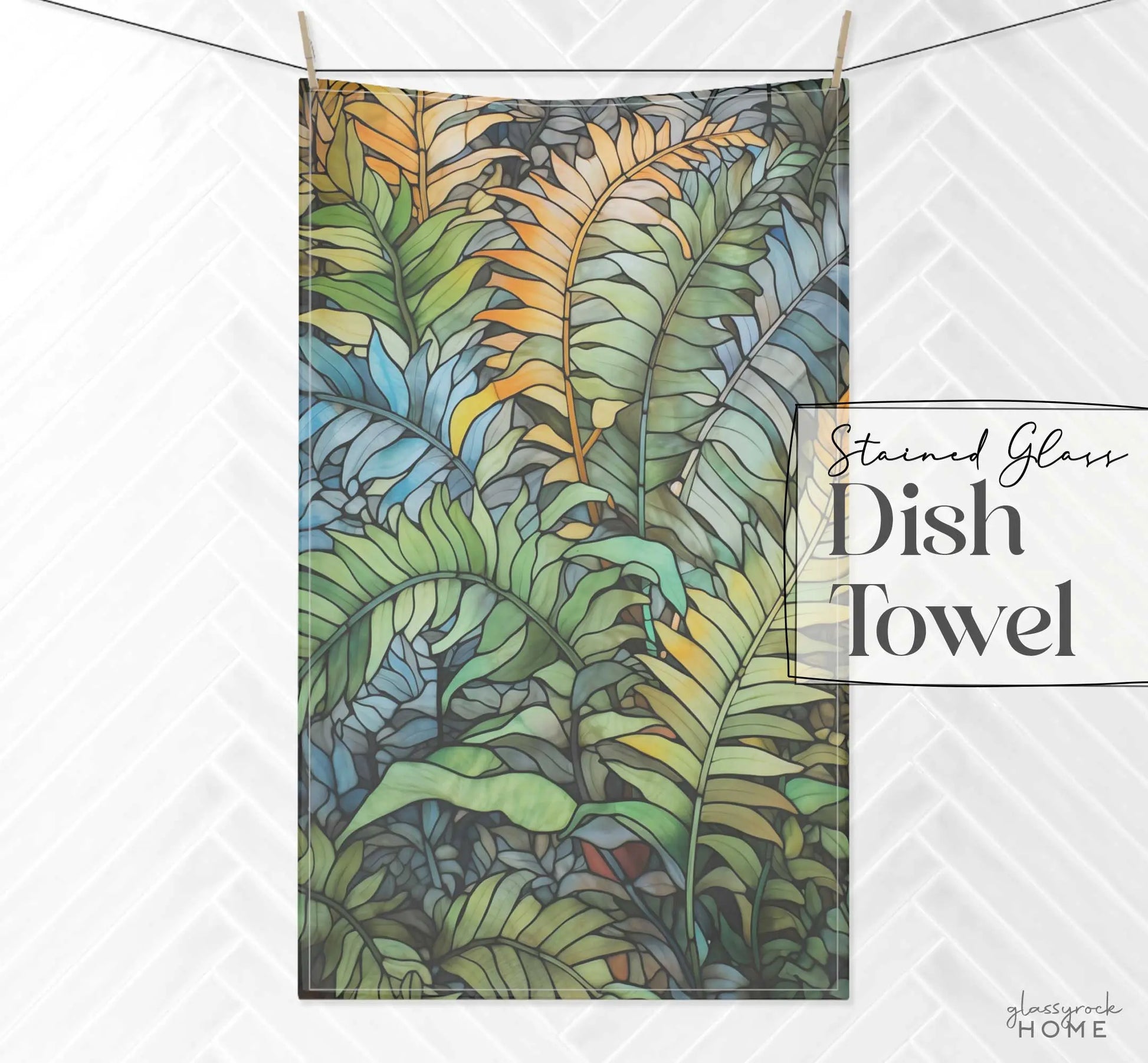 Dish towel featuring a stained glass-style design of overlapping blue, green, and yellow tropical leaves on a white herringbone-patterned background. The text reads Stained Glass Wild Ferns Dish Towel.