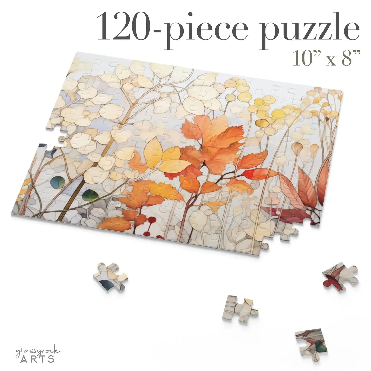 A partially assembled 120-piece Winter Botanicals Jigsaw Puzzle showcases a stained glass-inspired autumn design with orange and yellow leaves and light-colored flowers. Scattered pieces surround the puzzle, which is 10” x 8”, and labeled glassrock ARTS.