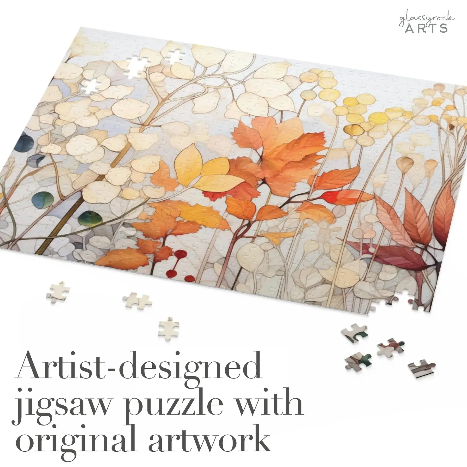 A partially completed jigsaw puzzle showcases abstract autumn leaves in orange, yellow, and brown against a light background. Scattered pieces add to the challenge. Text reads Artist-designed Winter Botanicals Jigsaw Puzzle with stained glass-inspired design.