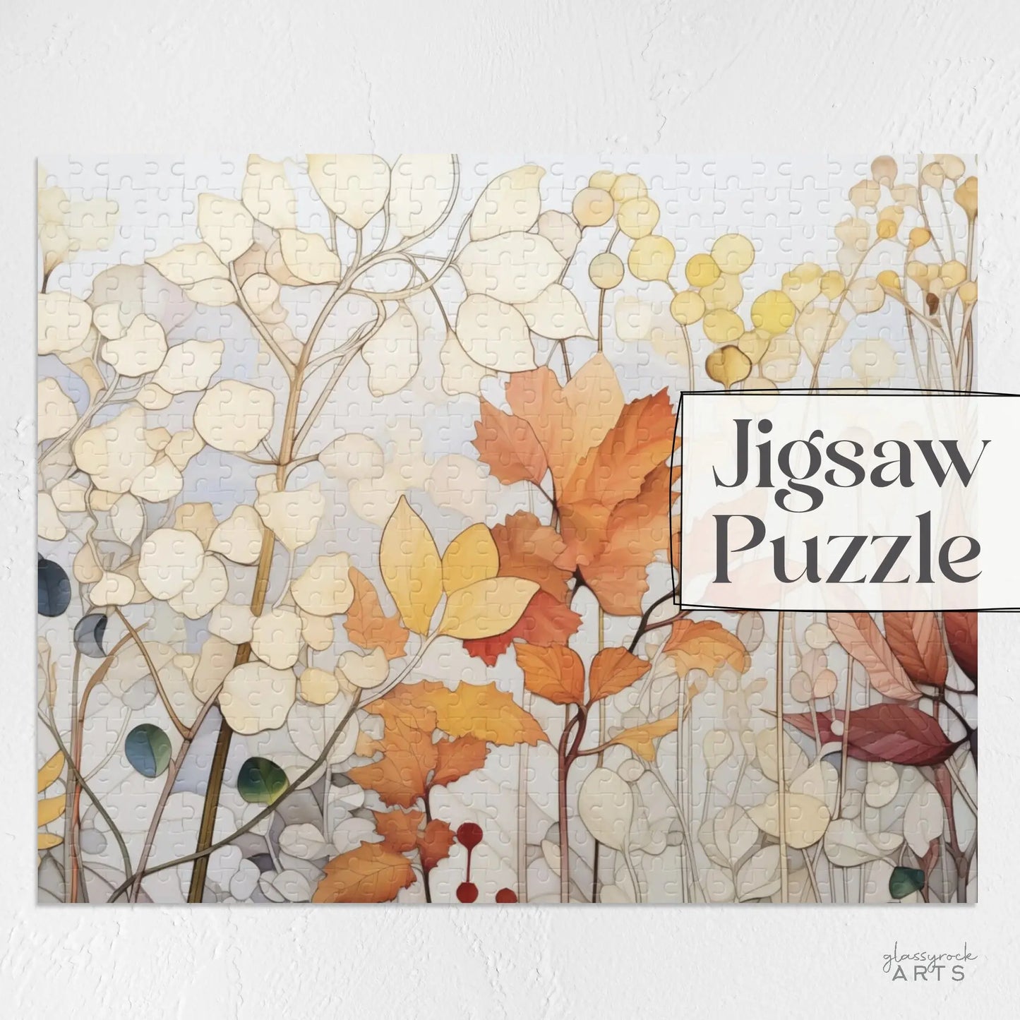 The Winter Botanicals Jigsaw Puzzle forms a stained glass-style scene of autumnal leaves in orange, yellow, and beige on a light background, with Jigsaw Puzzle in the upper right corner.