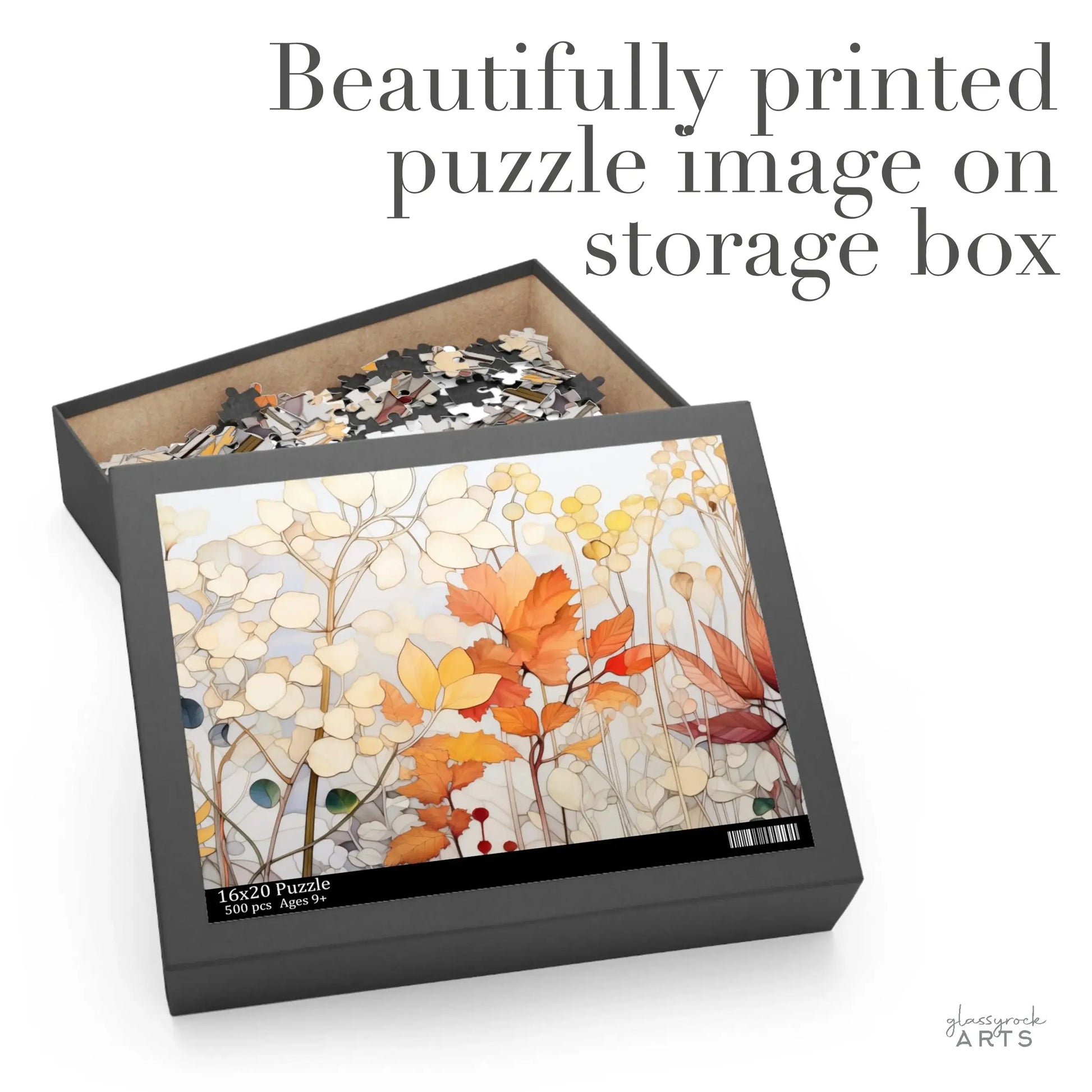 The Winter Botanicals Jigsaw Puzzle box, labeled as 16x20 Puzzle, 500-850 Pieces, features an autumn-inspired stained glass design with beige, orange, and red leaves. The open box reveals scattered pieces inside. Text reads, Beautifully printed puzzle image on storage box.