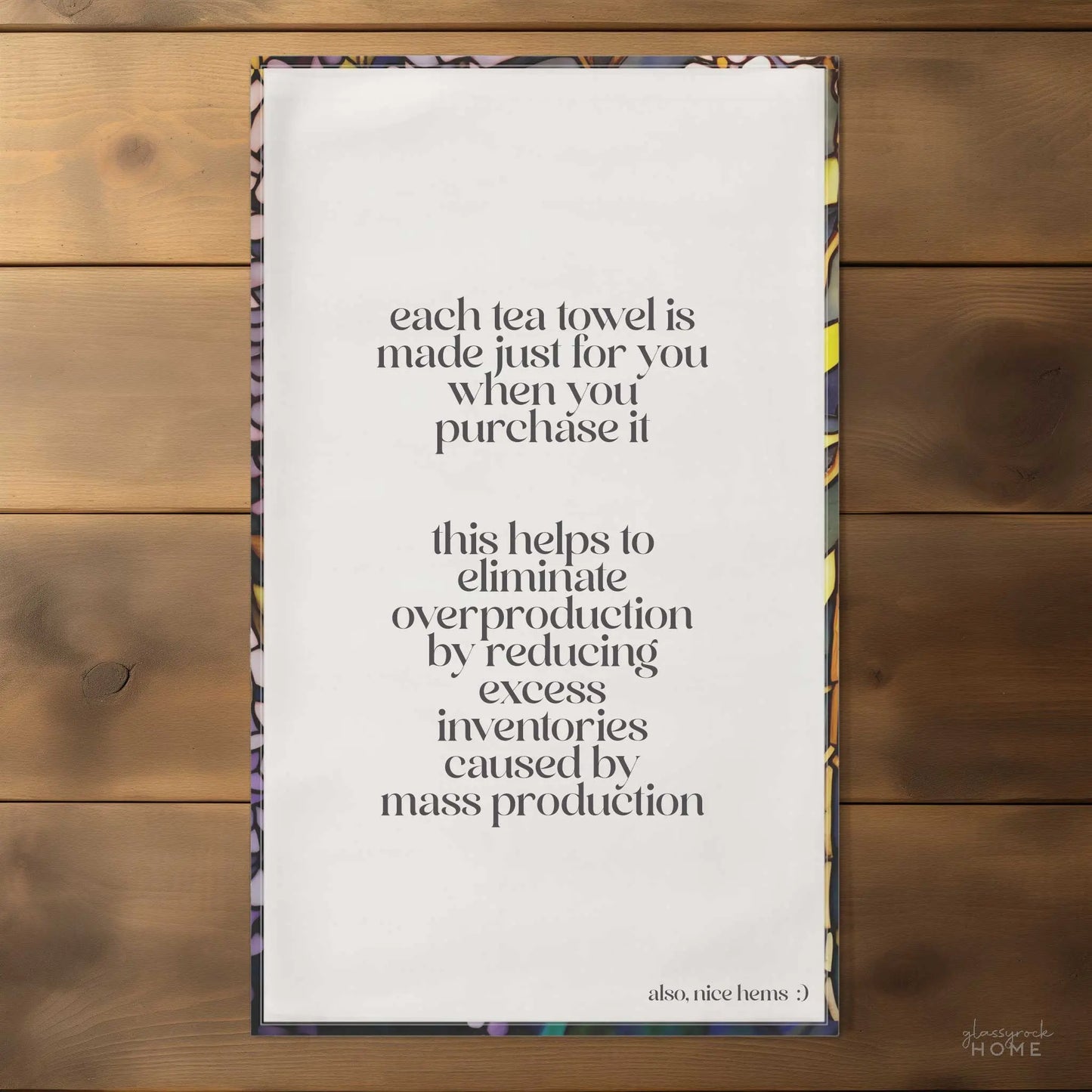 The Stained Glass Wisteria Dish Towel features a beautiful white wisteria design and carries an important message: purchasing this towel helps eliminate overproduction by reducing excess inventories associated with mass production. Made from natural cotton twill, it also includes a charming note that says, "also, nice hems :)".