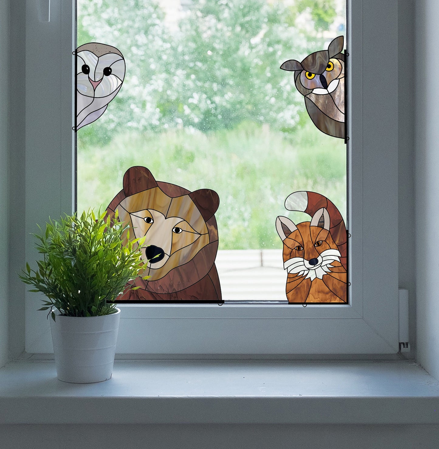 A window adorned with the vibrant Animal Stained Glass Pattern 9-Pack, featuring a bear, fox, owl, and cat design for intermediate hobbyists, adds charm. A potted plant on the sill overlooks lush greenery outside.