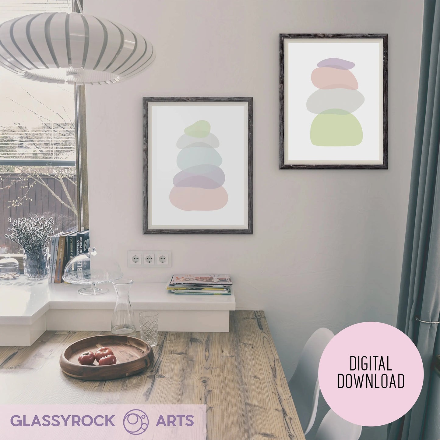 A minimalist dining area showcases a wooden table and bench. Two Pastel Clear Modern Stone Shapes art prints grace the white wall. A large window bathes the space in natural light, complementing the boho style. A wooden bowl of fruit and stacked books adorn the table.