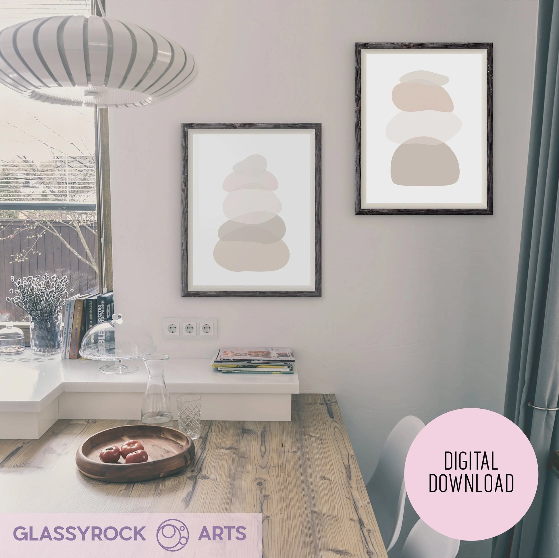 A minimalist kitchen featuring a wooden breakfast table and sunlight streaming through sheer curtains. On the wall are two Ombre Nude Stone Shapes Digital Artwork prints in neutral tones, labeled as Instant Digital File.