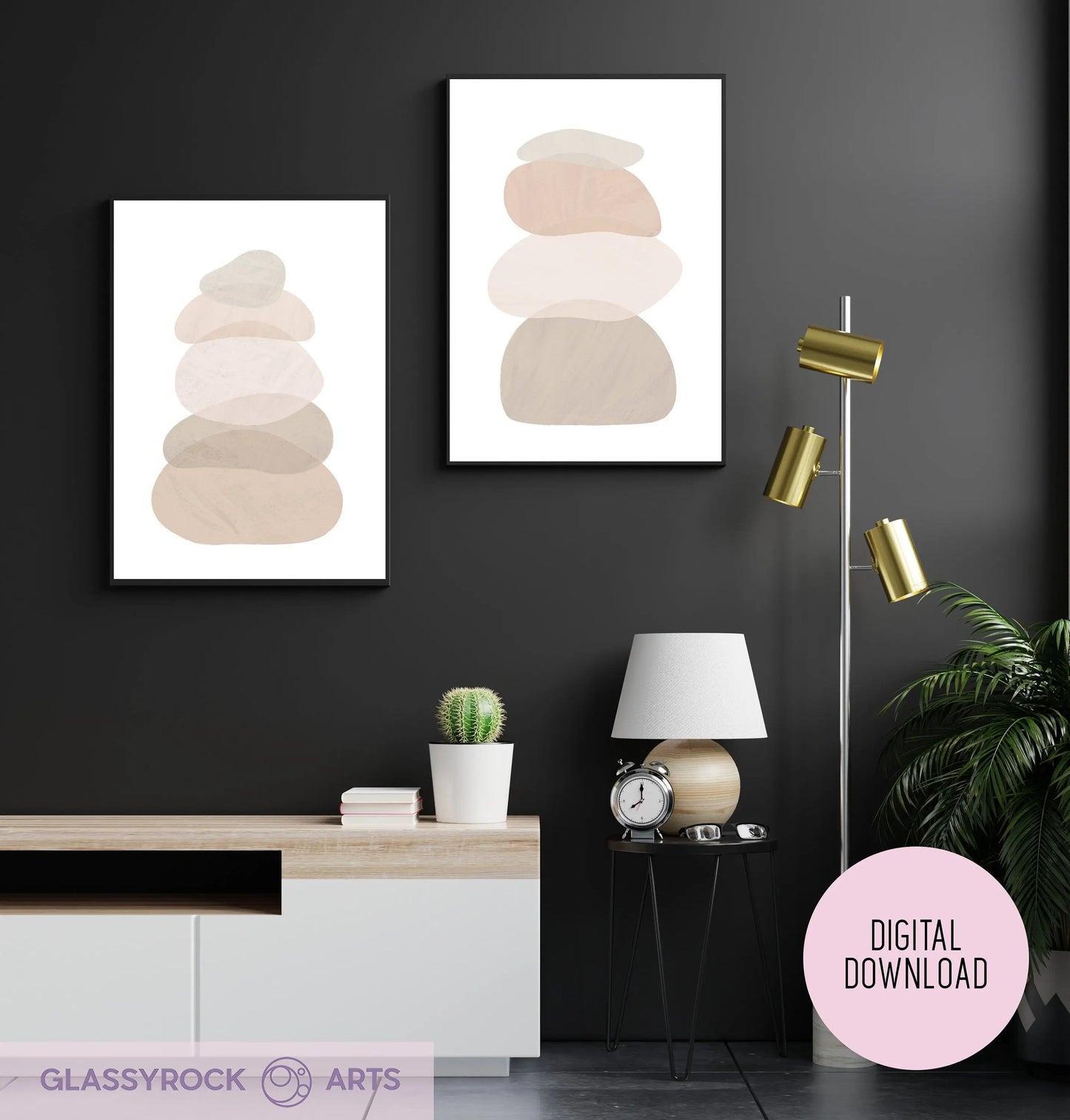 A modern living room with a dark wall features two Ombre Nude Modern Stone Shapes digital art prints. Nearby, a floor lamp stands beside a white side table holding a lamp, plant, and clock. A potted cactus on the console completes the boho Japandi Scandi decor style.