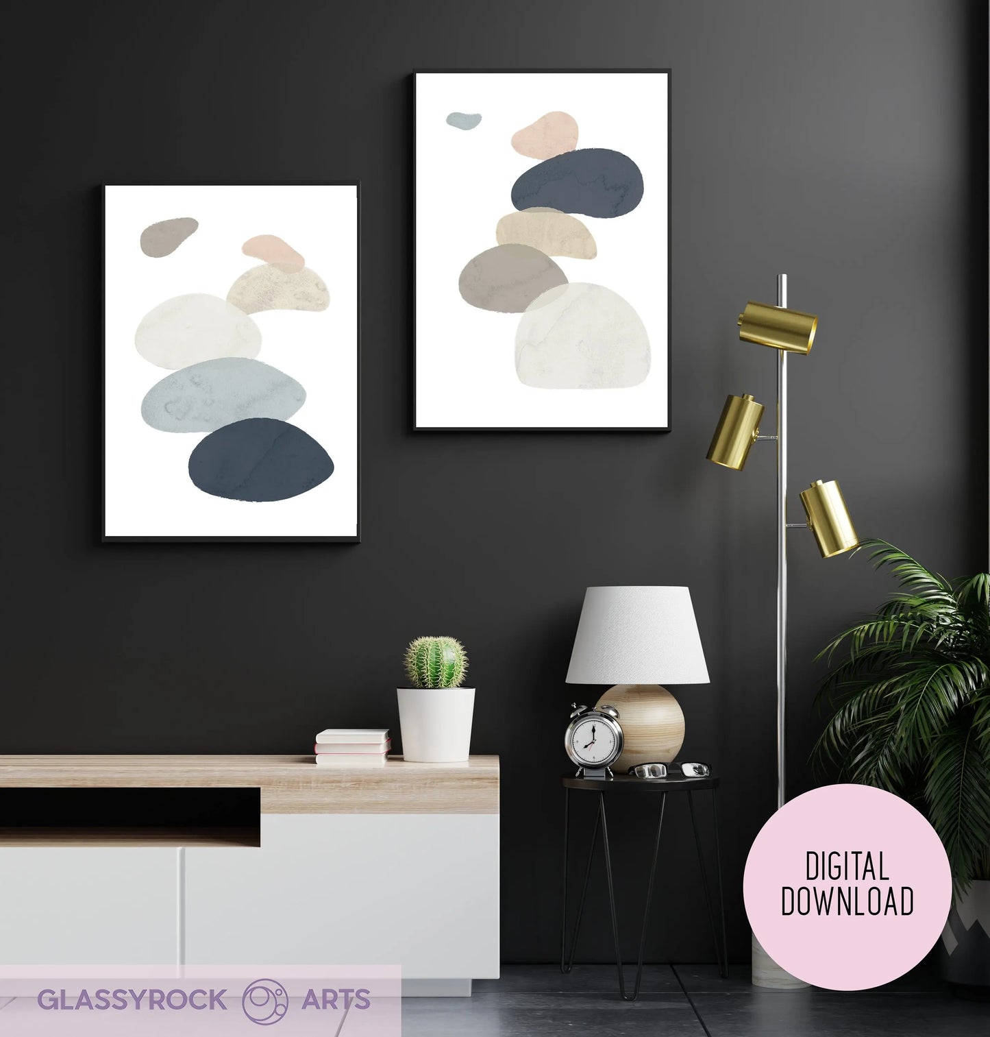 A modern living room with a black wall features the Abstract Watercolor Stone Shapes Digital Art printables. A sideboard holds decor, with a tall gold lamp, a small white lamp, and a potted plant nearby. A Digital Download label indicates its an instant digital file.