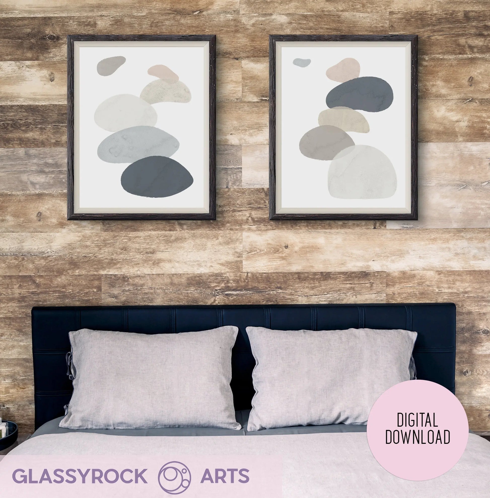 Two Abstract Watercolor Stone Shapes prints from Glassyrock Arts hang above a dark blue headboard and gray-pillowed bed, framed by wooden frames against a rustic wood backdrop; marked as a digital download.