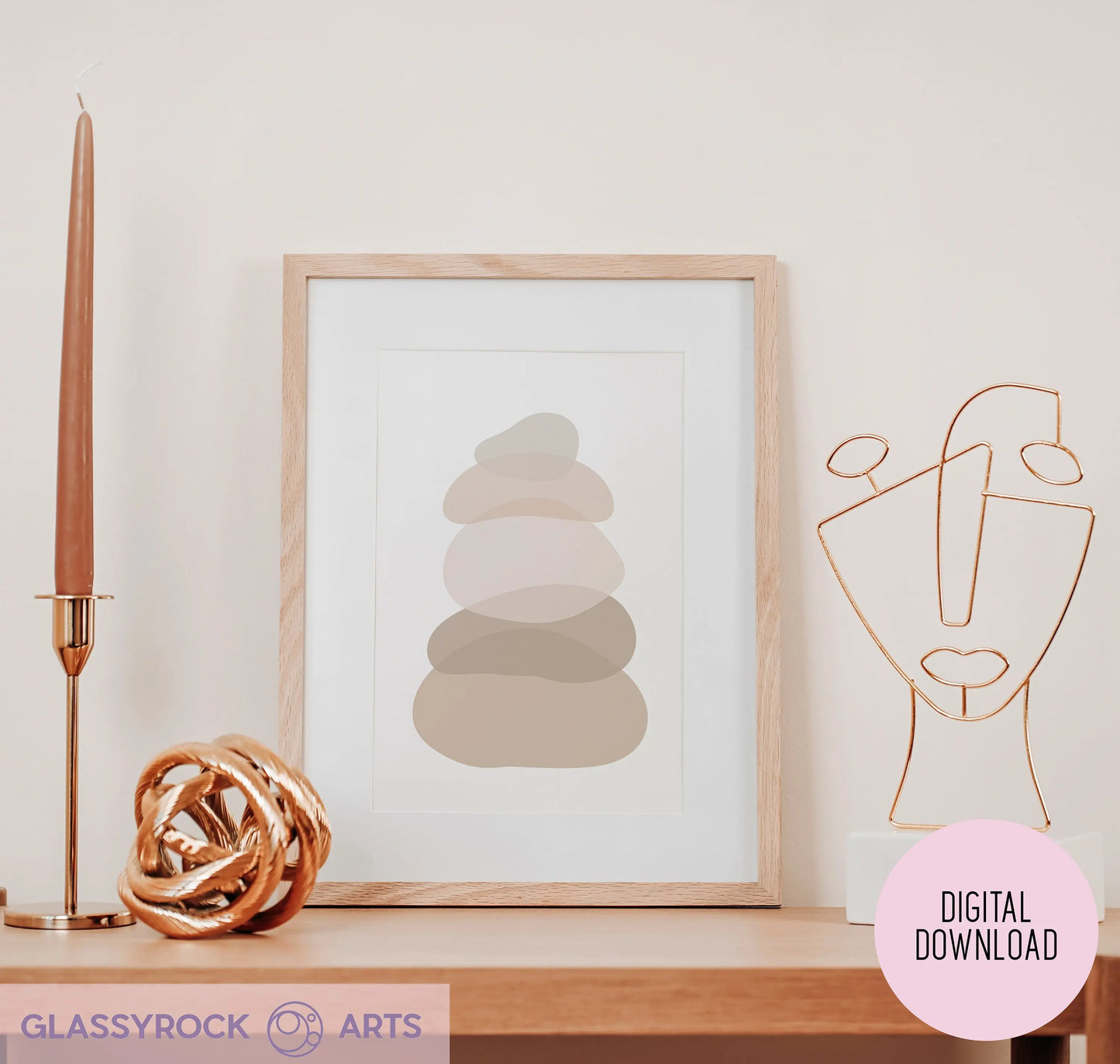 The Ombre Nude Stone Shapes Digital Artwork is framed and sits on a shelf with a tall candle and bronze geometric face sculpture. Glassyrock Arts offers this as an Instant Digital File, emphasizing digital art printables.