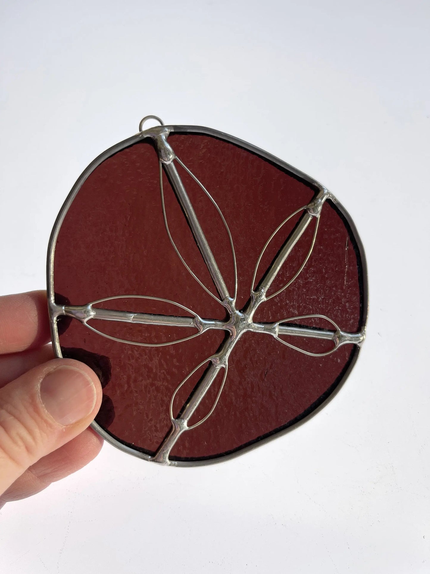 A purple handmade stained glass sand dollar with handworked wire accents, christmas tree ornaments, suncatchers