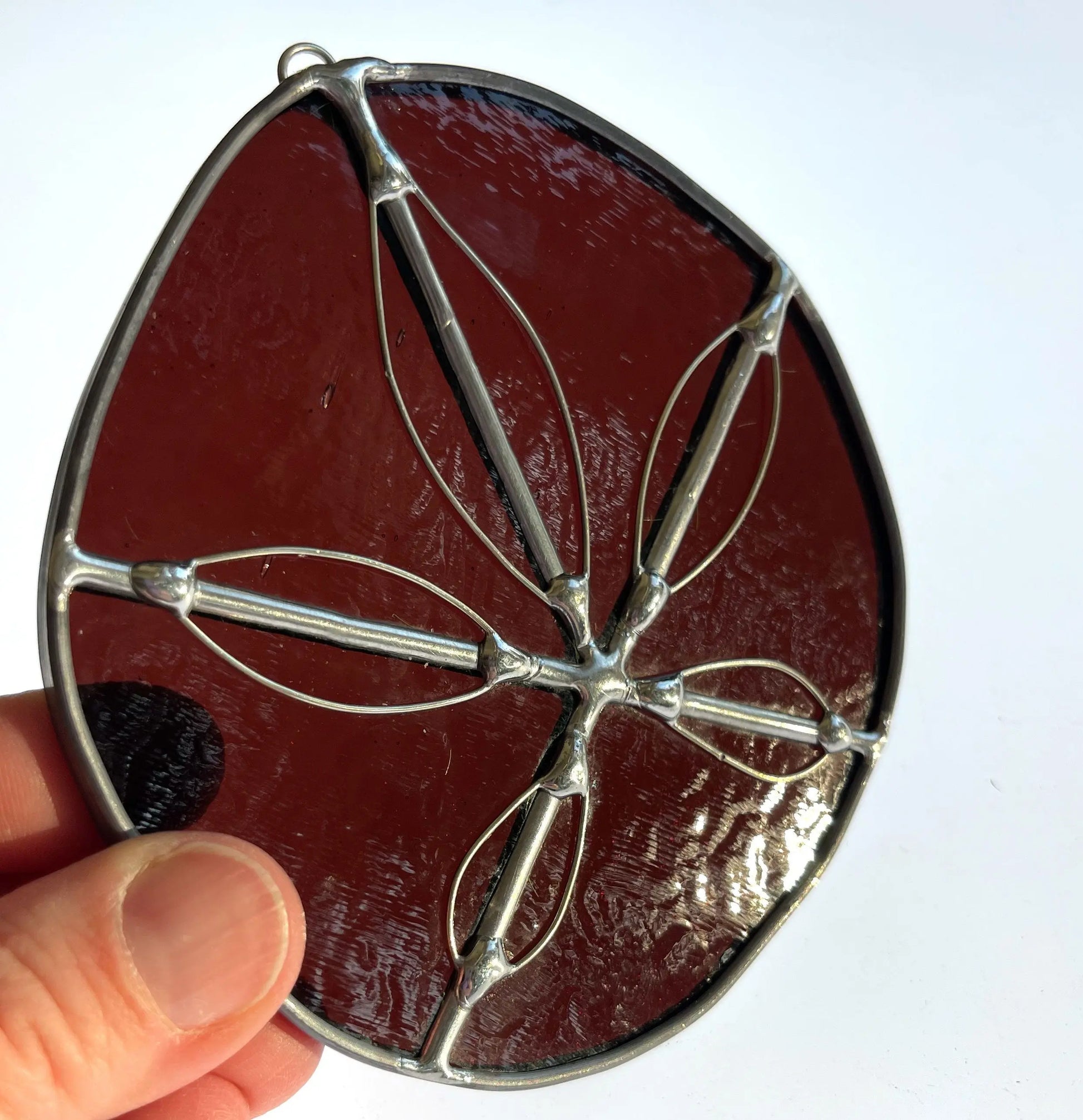 A purple handmade stained glass sand dollar with handworked wire accents, christmas tree ornaments, suncatchers