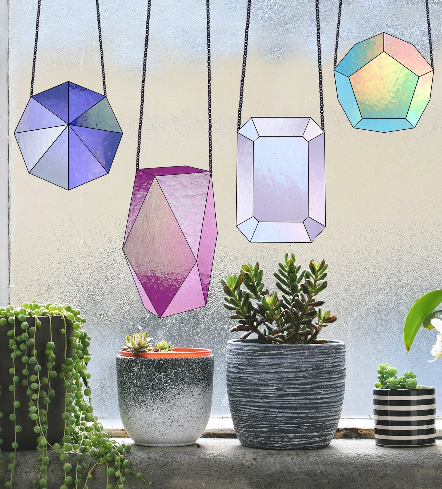 Hanging stained glass suncatchers in geometric shapes and various colors near a window. Below are three plant pots with different succulent arrangements. The background features a frosted window.