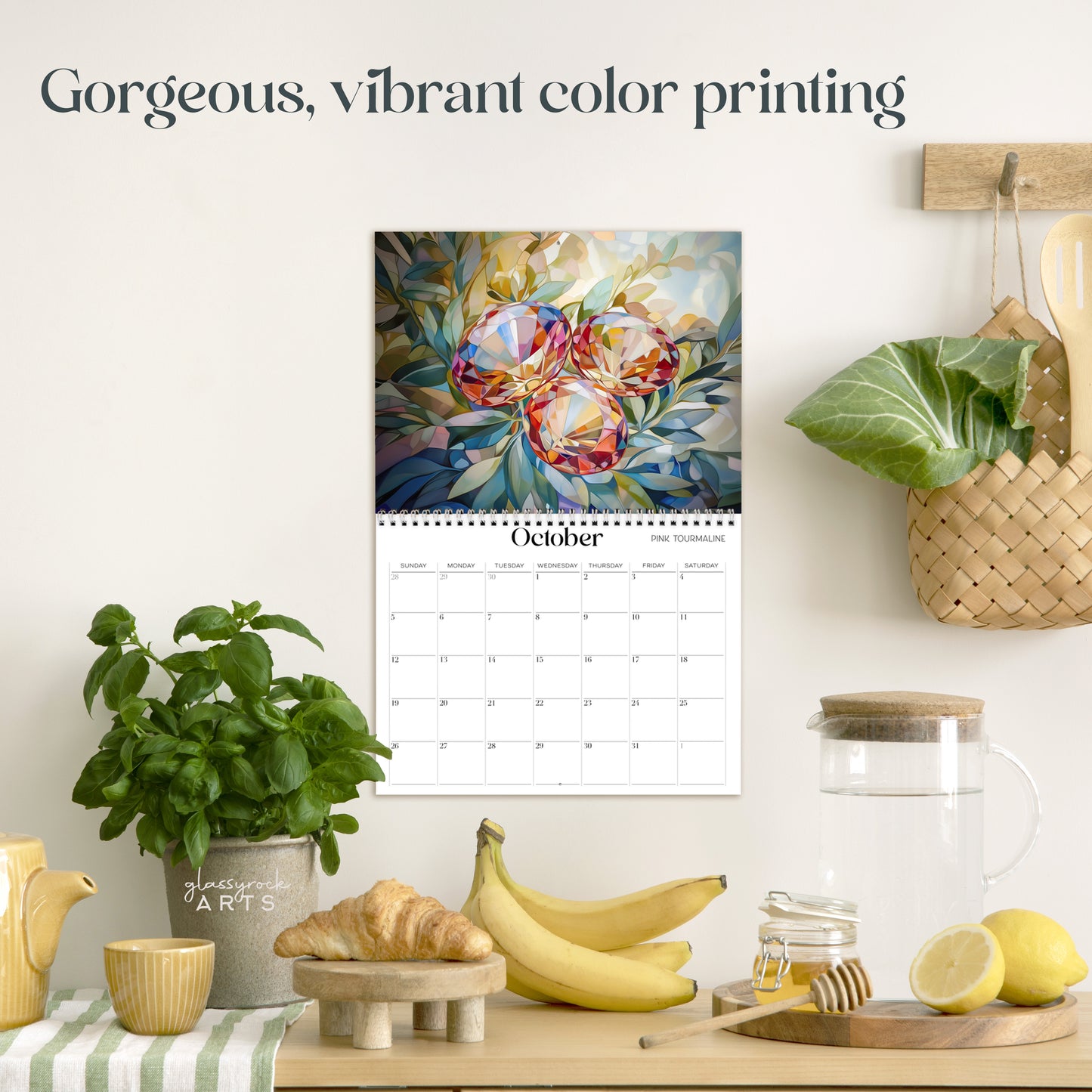 The birthstones calendar hanging in a kitchen with kitchen tools below on a counter. It has gorgeous, vibrant color printing on premium paper.