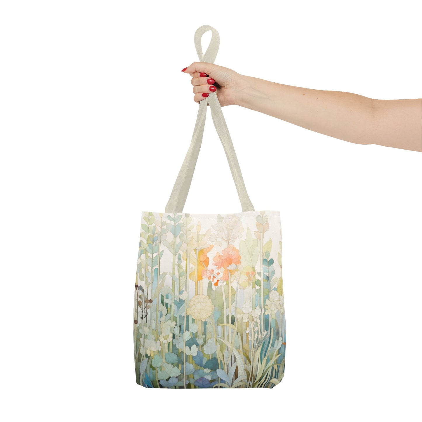 A hand with red-painted nails holds a Stained Glass Pastel Flowers Tote Bag, featuring vibrant flowers and green plants on white. This original artist design, made from durable polyester, offers style and longevity in three sizes.