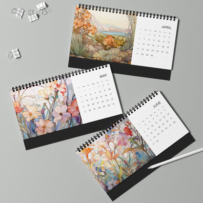 Three 2025 Desk Calendars - Botanicals for April, May, and June are laid out on a light gray surface. Each features botanical floral illustrations and monthly grids. The high-quality paper stock complements the designs. Silver binder clips and a white pen are nearby.