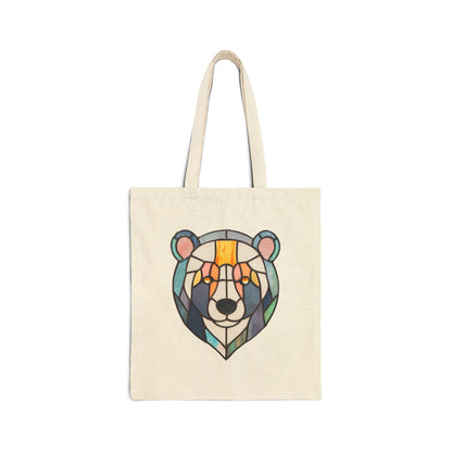 The Stained Glass Patchwork Bear Cotton Canvas Tote Bag in beige showcases a geometric bear face design in orange, blue, and black shades. Featuring Noelle Barnes original artwork, this minimalist piece has two sturdy handles and is made from heavyweight cotton canvas.