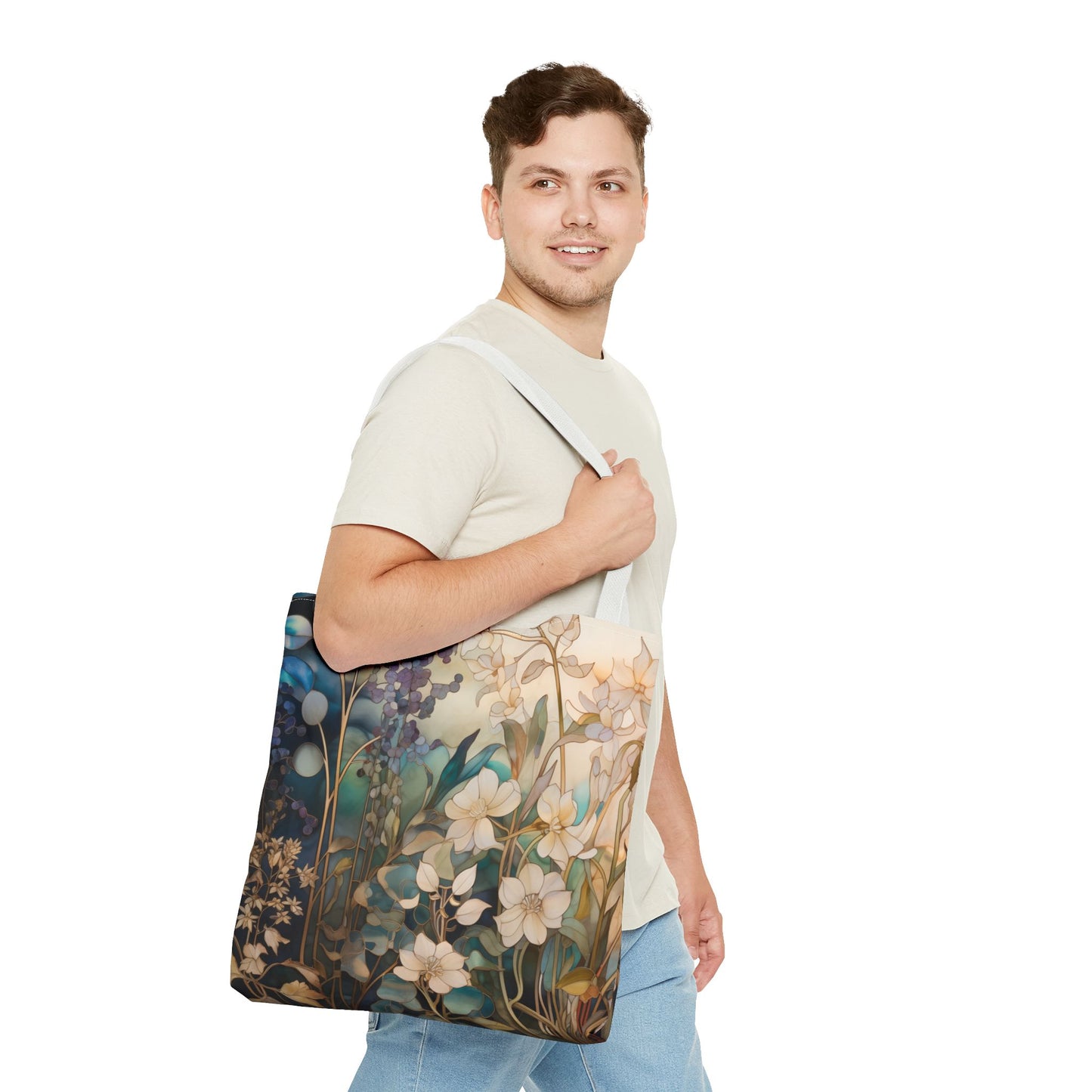 A man in a light shirt and jeans is standing and holding a Stained Glass Midnight Flowers Tote Bag.