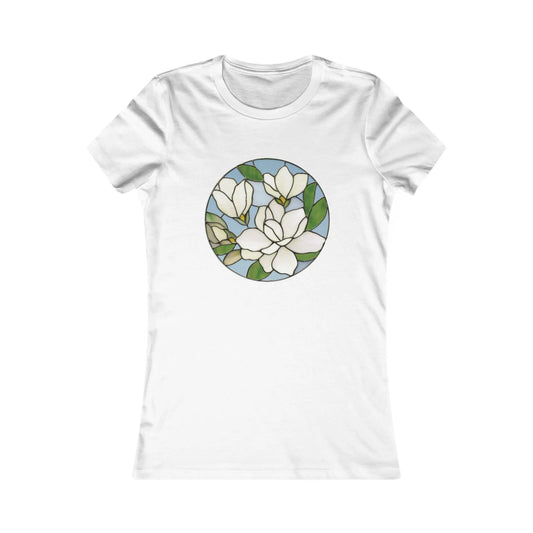 The Stained Glass Magnolia Womens Tee Shirt features a circular stained glass design with white flowers and green leaves on a light blue background, offering comfort and an artistic touch for those who value sustainable fashion.