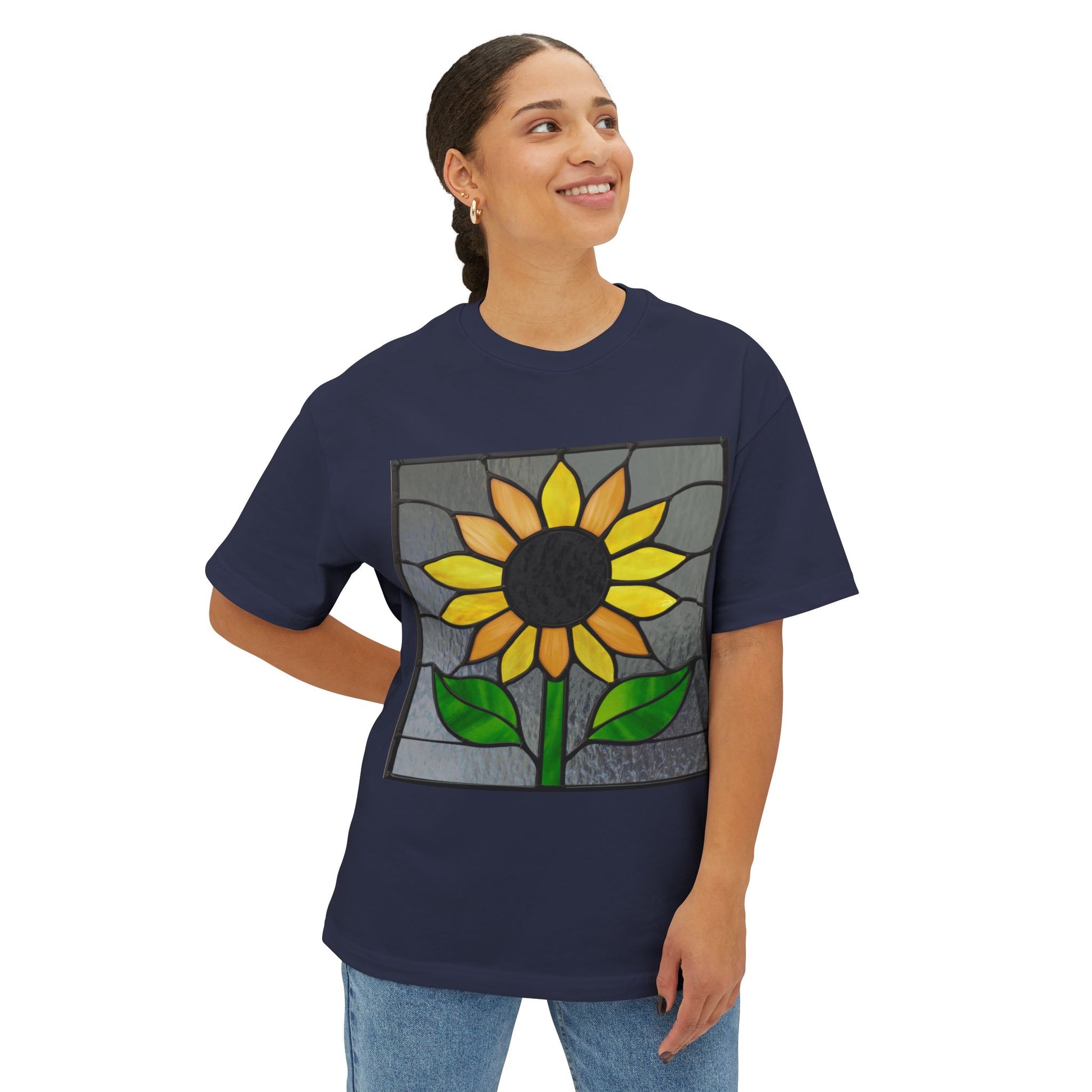 A person wearing a dark blue Stained Glass Sunflower Oversized Tee Shirt by Bella+Canvas stands, looking off to the side.