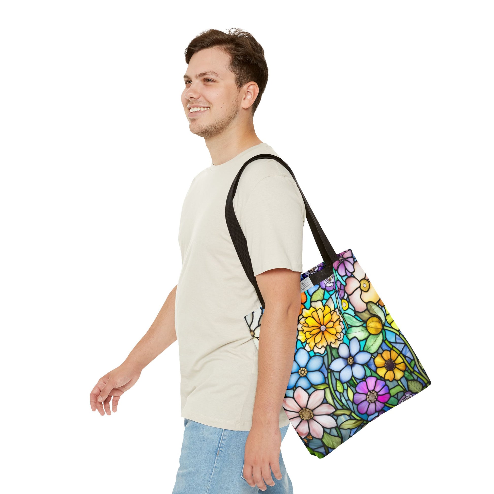 A person in a beige T-shirt and denim shorts carries a Stained Glass Folk Art Flowers Tote Bag over their shoulder, walking forward and smiling.