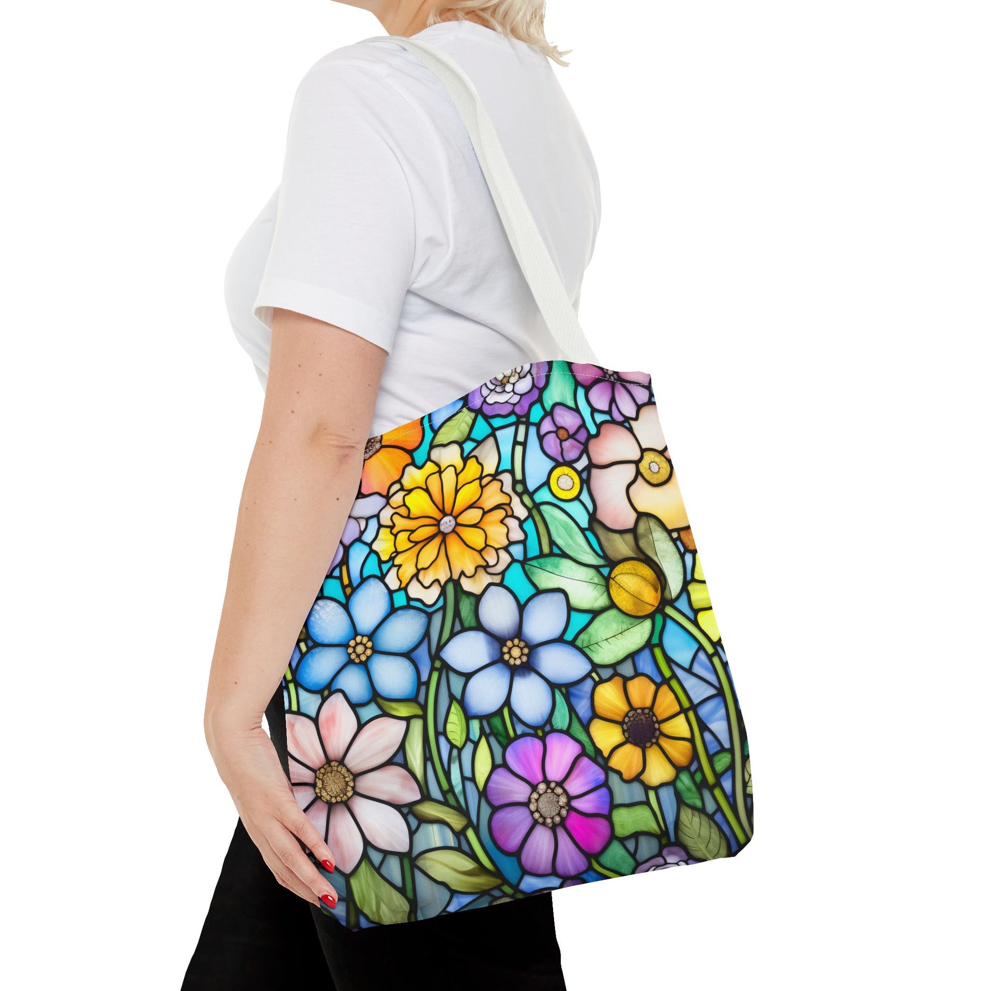 A person in a white t-shirt carries the Stained Glass Folk Art Flowers Tote Bag, featuring a durable polyester build with an original stained glass design of colorful flowers on a white background.