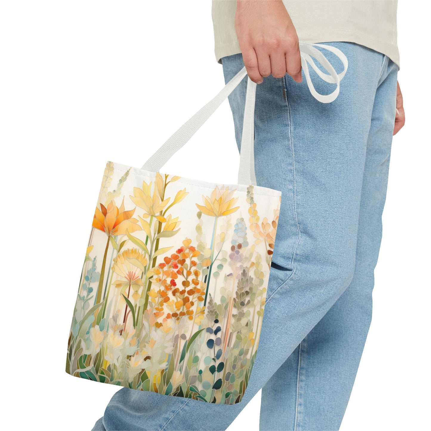 A person carrying a Stained Glass Fall Flowers Tote Bag with a colorful floral design is dressed in light blue jeans and a light-colored shirt. The bag, made from durable polyester materials, ensures it withstands daily use while showcasing an original artist's design. Three different sizes are available for the tote bag.