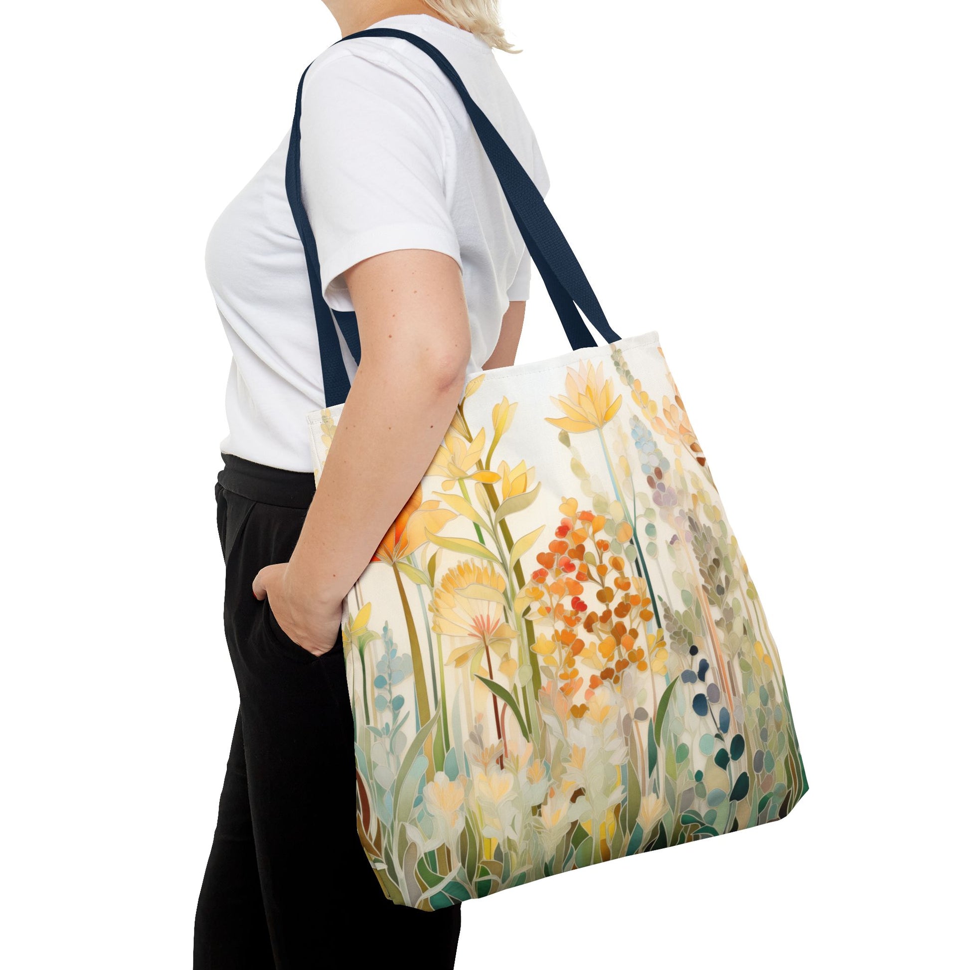 A person wearing a white shirt and black pants holds the Stained Glass Fall Flowers Tote Bag, made from durable polyester. The side view features vibrant yellow and orange flowers, showcasing an original artist design that adds flair to the ensemble.