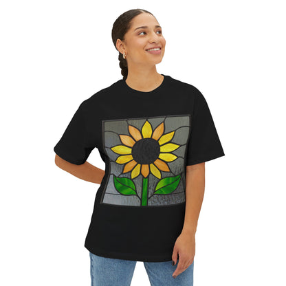 A person smiles and looks to the side while wearing a Stained Glass Sunflower Oversized Tee Shirt, featuring an artist-designed sunflower in a stained glass style on the front.