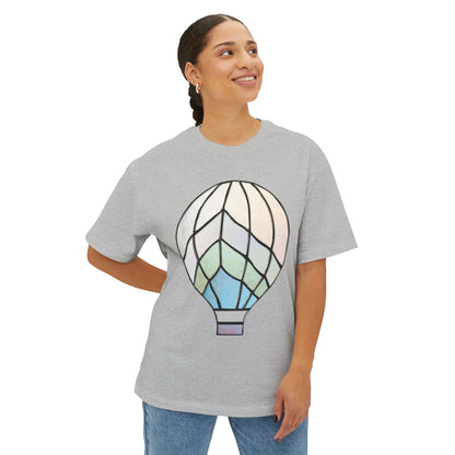 A person wearing a Stained Glass Hot Air Balloon Oversized Tee Shirt in light grey stands against a plain white background, smiling and looking off to the side.