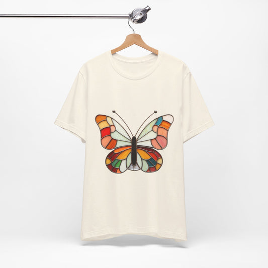 A Stained Glass Groovy Butterfly Unisex Tee Shirt by Bella+Canvas featuring a vibrant butterfly design is hanging on a wooden hanger suspended from a metal rod.