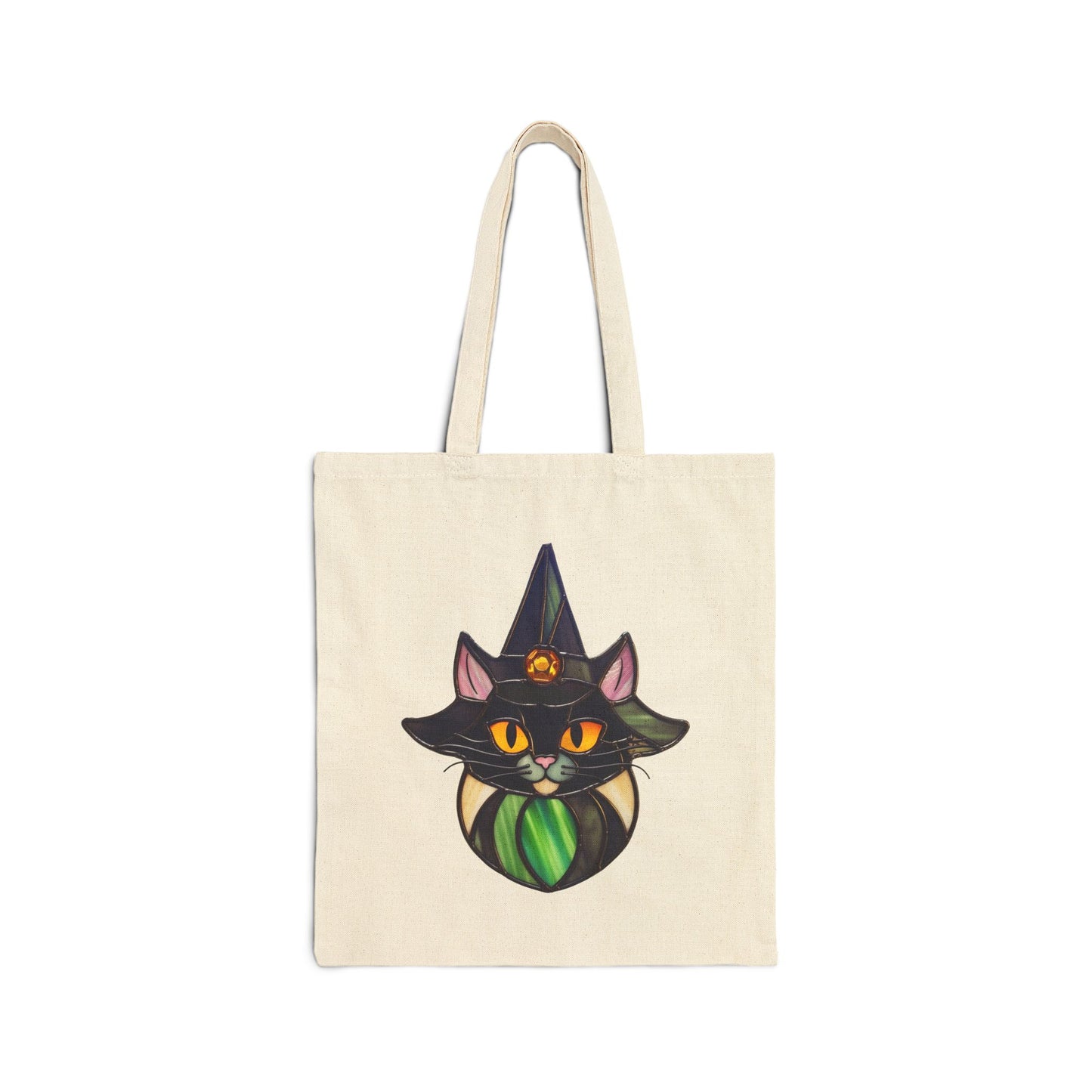 A beige cotton canvas tote bag named Stained Glass Cat Witch displays a black cat in a witch hat and cloak with a stained glass design by Noelle Barnes. The cats bright orange eyes twinkle, and its hat features a gemstone, all against a crisp white background.