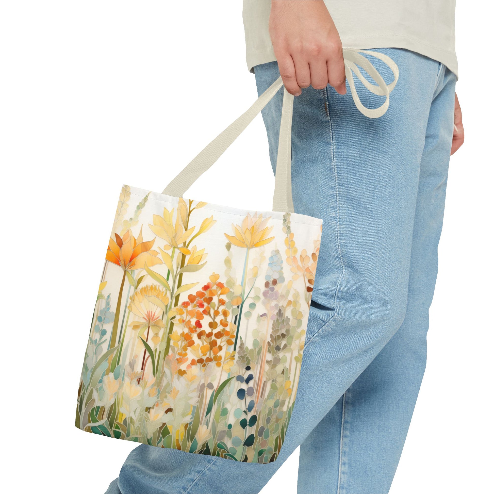 A person holds a Stained Glass Fall Flowers Tote Bag, showcasing its vibrant floral design. They wear light blue jeans and a pale shirt against a white backdrop.