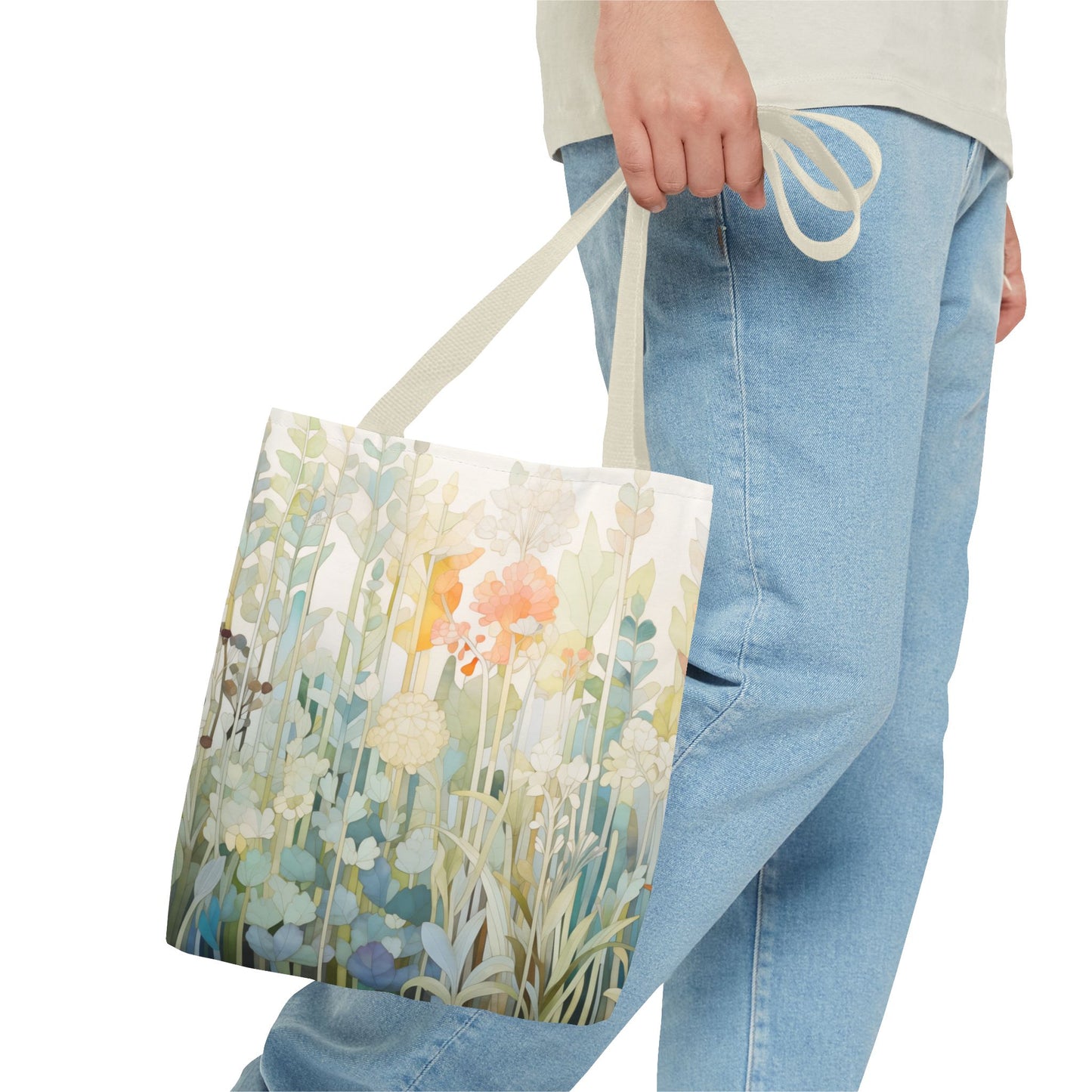 A person holds a Stained Glass Pastel Flowers Tote Bag, its floral design vibrant with colors and foliage. Made from durable polyester, it pairs perfectly with their light blue jeans and light-colored shirt. Available in 3 sizes.