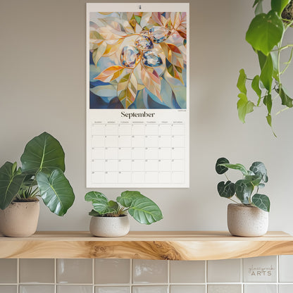 The birthstones calendar, a 2025 monthly wall calendar with gem-themed original artwork, hanging on a wall surrounded by plants. The September page shows sapphires.