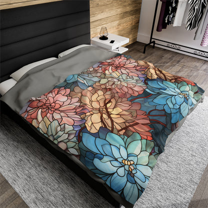 The rooms modern decor features a black headboard, a nightstand with a lamp, and a clothes rack. A plush Stained Glass Flowers blanket with large, stylized flowers in blue, red, yellow, and green adorns the bed.