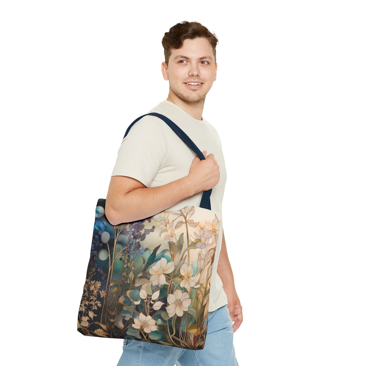 A man in a light beige t-shirt and blue jeans carries the Stained Glass Midnight Flowers Tote Bag, featuring a floral design with blue, beige, and white flowers on a dark background. Crafted from durable polyester materials, its displayed against a plain white backdrop.