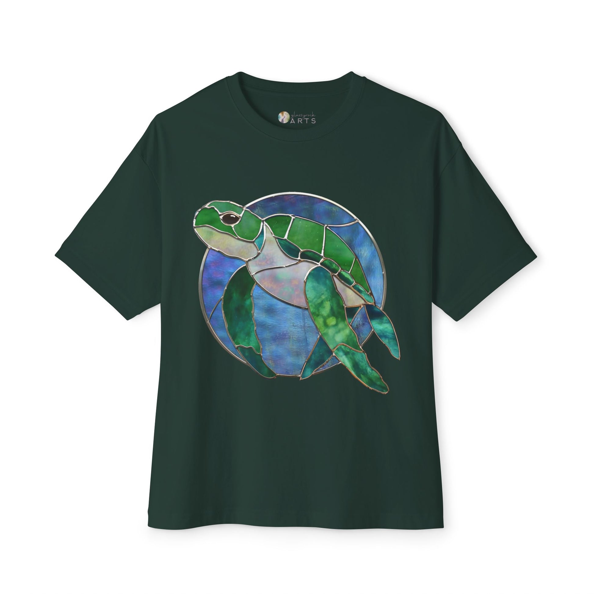 A Bella+Canvas dark green t-shirt named "Stained Glass Turtle Oversized Tee Shirt," featuring an artistic design by Noelle Barnes of a sea turtle in blue and green shades on the front.