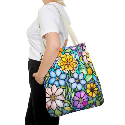 A person dressed in a white shirt and black pants carries a vibrant Stained Glass Folk Art Flowers Tote Bag, an original design with blue, yellow, pink, and purple flowers on a white background. Available in three sizes.