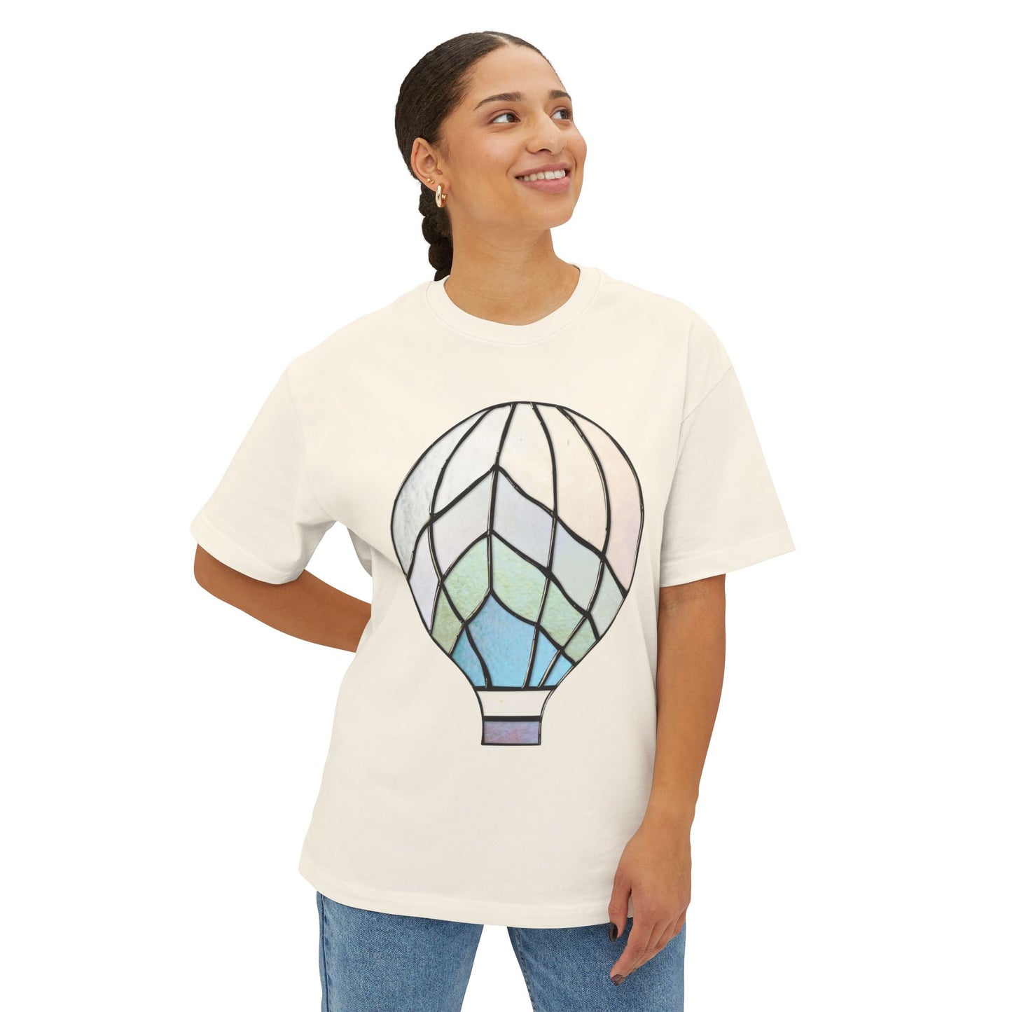 A person wearing a Stained Glass Hot Air Balloon Oversized Tee Shirt in white, featuring a pastel-colored hot air balloon graphic, standing with one hand on hip and smiling.