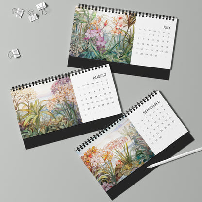 Three spiral-bound 2025 Desk Calendars - Tropical Flowers for July, August, and September feature botanical illustrations, displayed on a light gray surface with binder clips and a pen nearby. Made in the USA.