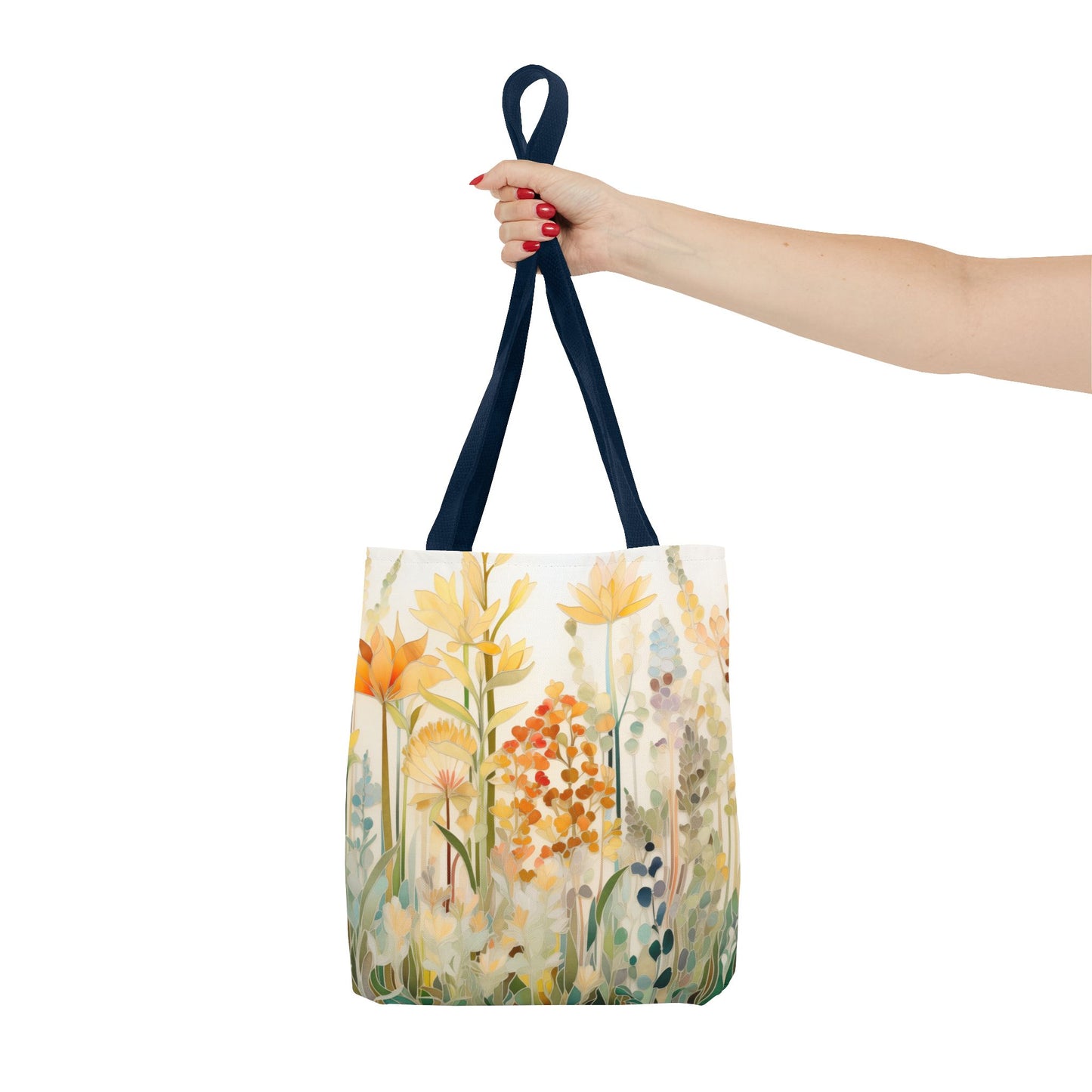 A hand with red nail polish holds the Stained Glass Fall Flowers Tote Bag with dark blue handles, showcasing an original artist design of colorful flowers in shades of orange, yellow, and green on a light background.