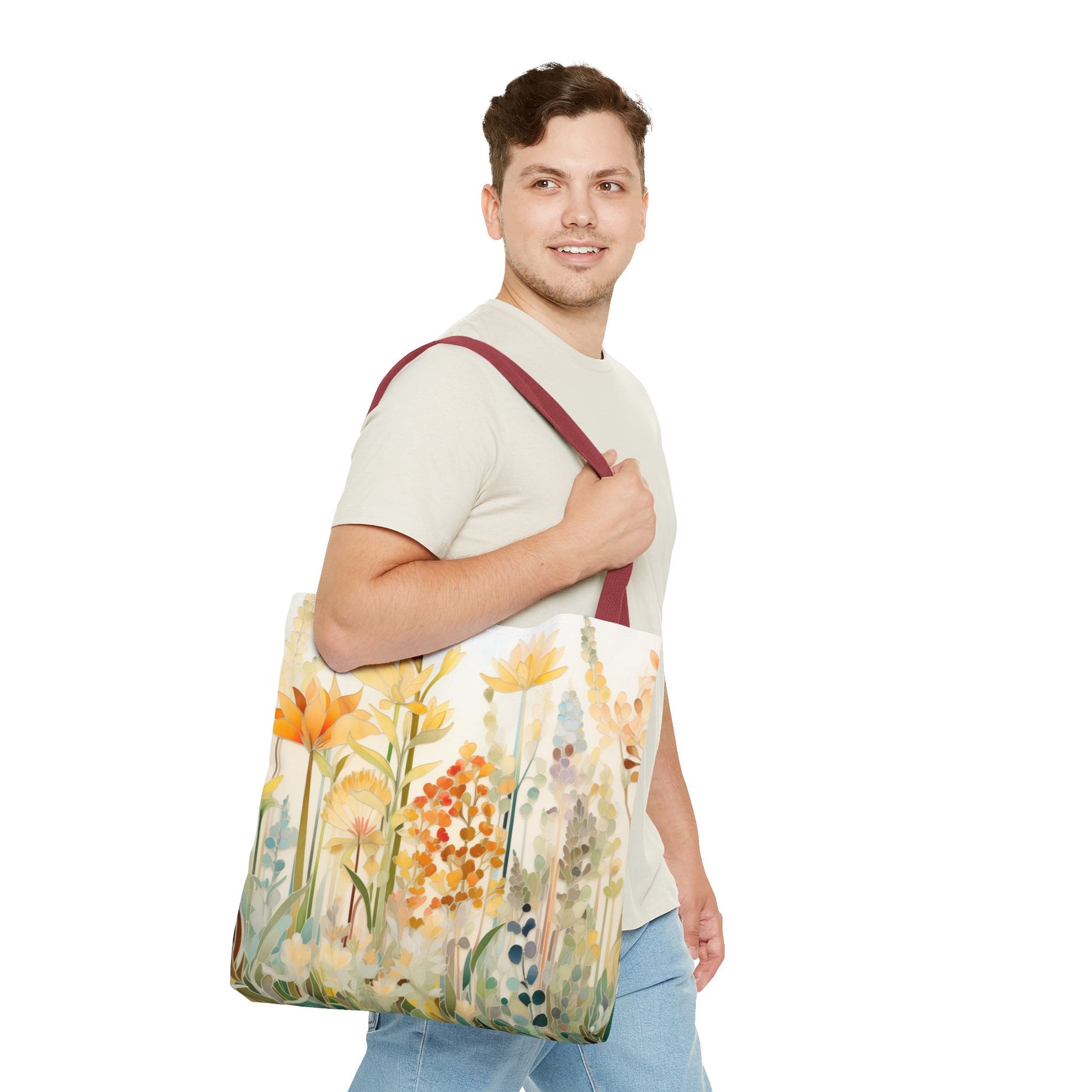 A person wearing a light beige shirt and blue jeans carries the Stained Glass Fall Flowers Tote Bag featuring colorful floral patterns on a plain white background. Crafted from durable polyester, it boasts a dark red strap and showcases vivid artistry. Available in 3 sizes.