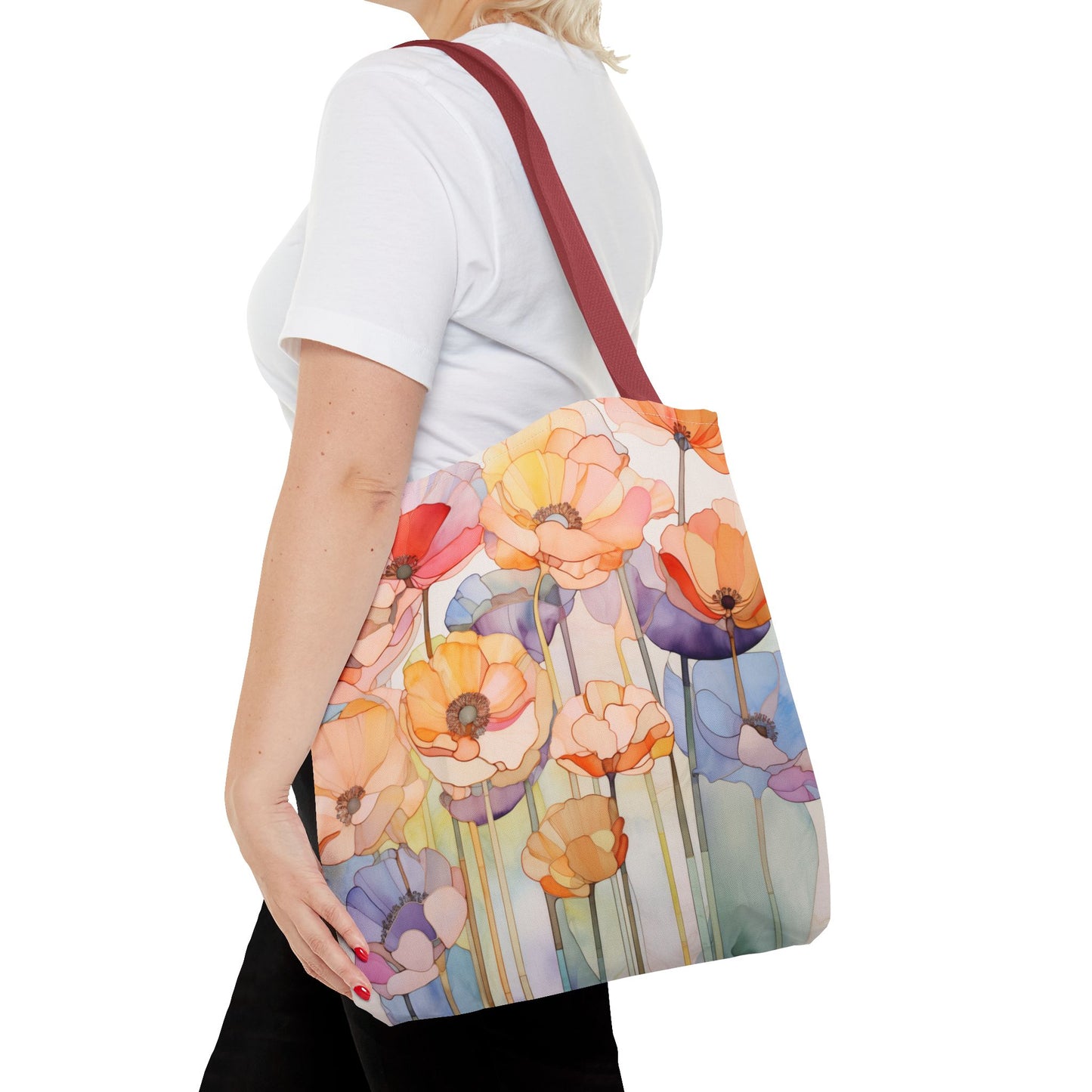 A person wearing a white shirt and black pants carries a Stained Glass Poppy Flowers Tote Bag, available in three sizes, decorated with colorful floral patterns over their shoulder.