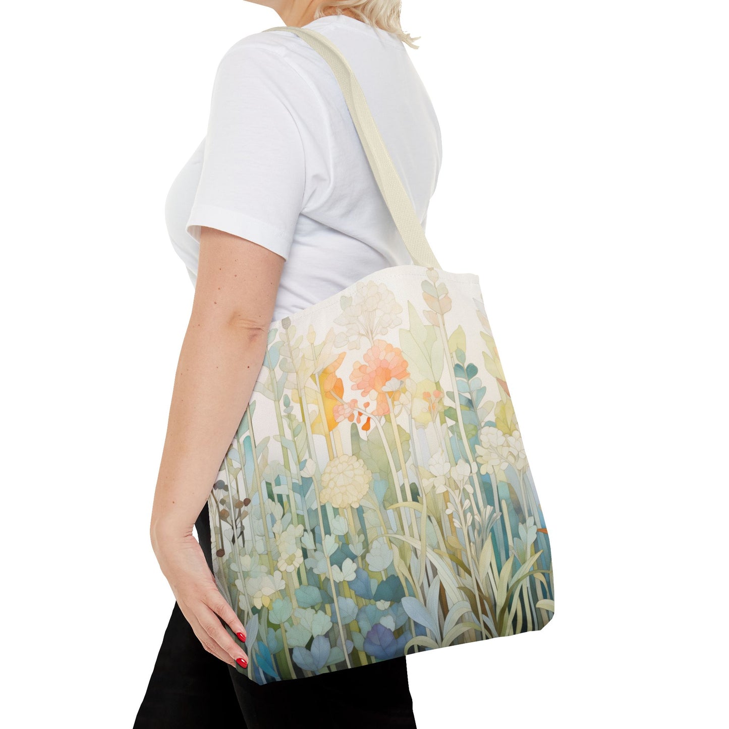 A person in a white t-shirt holds the Stained Glass Pastel Flowers Tote Bag. Available in three sizes, this durable polyester tote displays an original artist design of pastel flowers and greenery. Its photographed from the side against a white background.