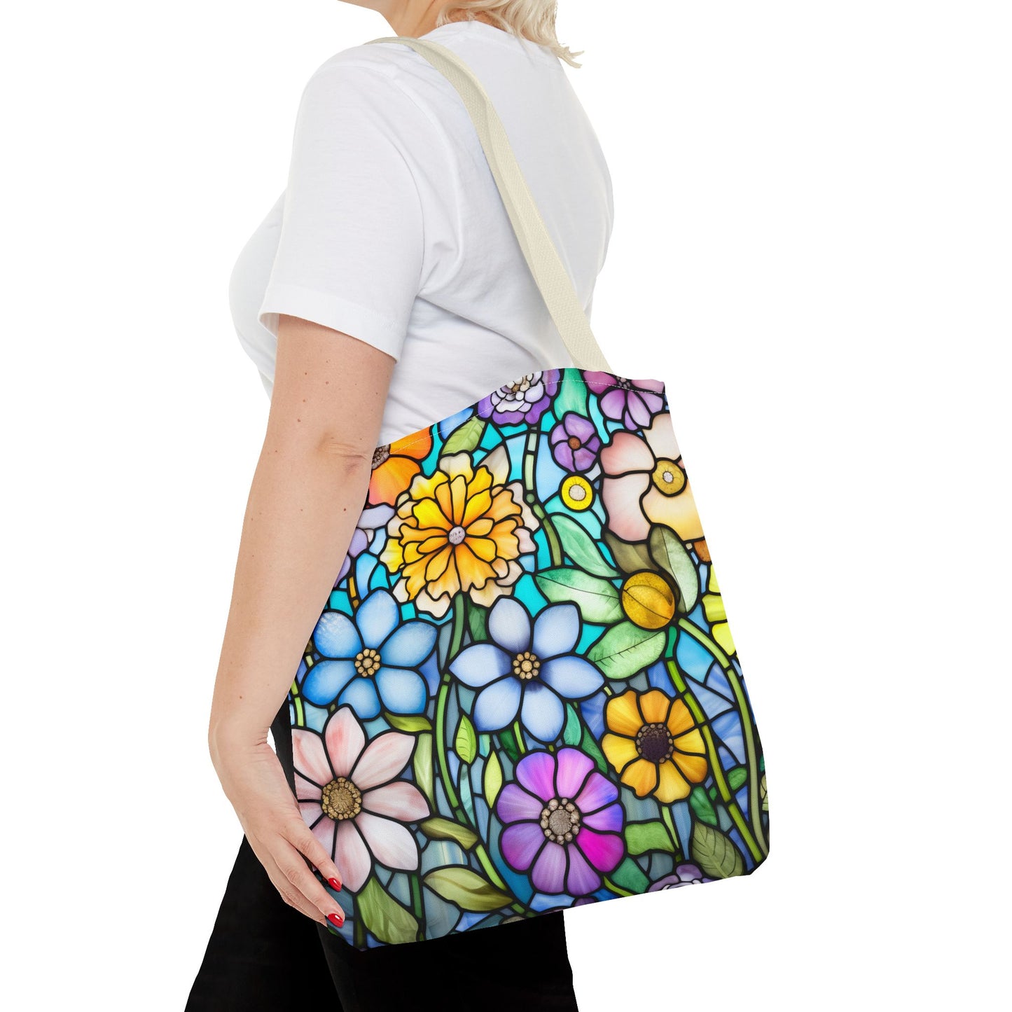 A person holding the Stained Glass Folk Art Flowers Tote Bag, which showcases a vibrant floral design made from durable polyester materials, available in three different sizes.