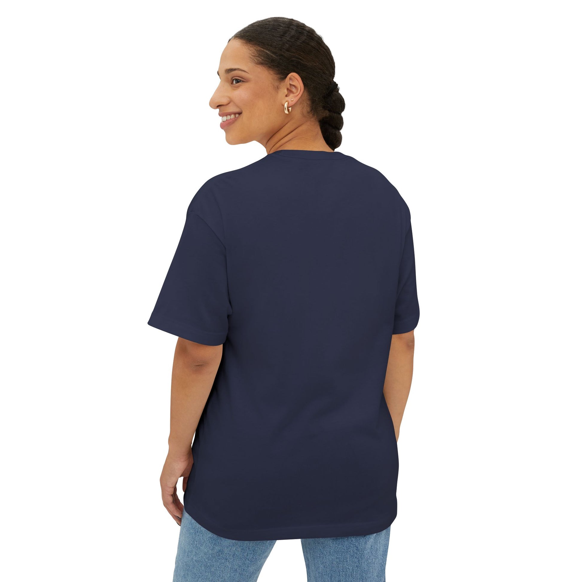 A person with braided hair is wearing a Stained Glass Sunflower Oversized Tee Shirt in navy blue and light blue jeans, standing and looking back over their shoulder.