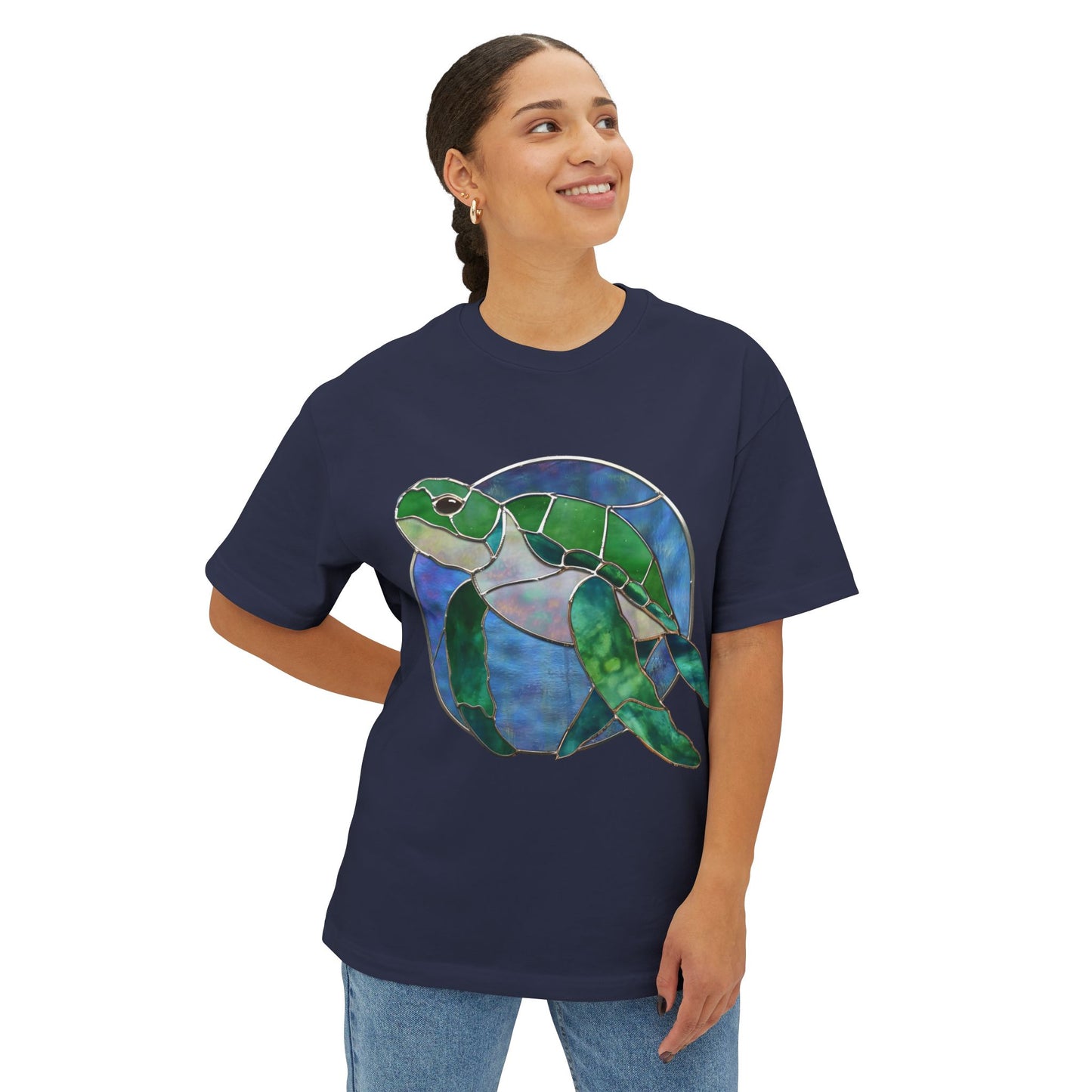 A person dressed in a Stained Glass Turtle Oversized Tee Shirt by Bella+Canvas, featuring a vibrant sea turtle design in navy blue, is smiling and looking upwards.