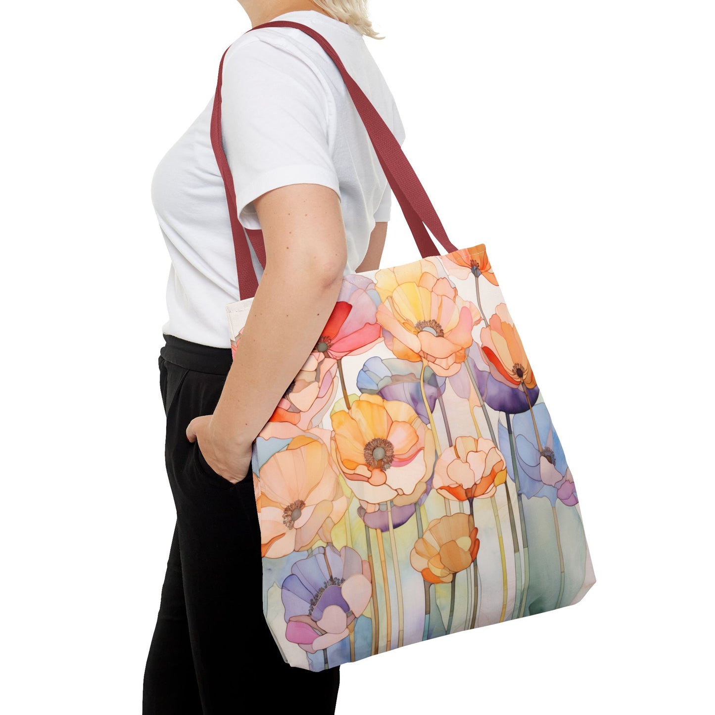 A person wearing a white shirt and black pants carries the Stained Glass Poppy Flowers Tote Bag, which is made from durable polyester and features a colorful floral design with red handles.