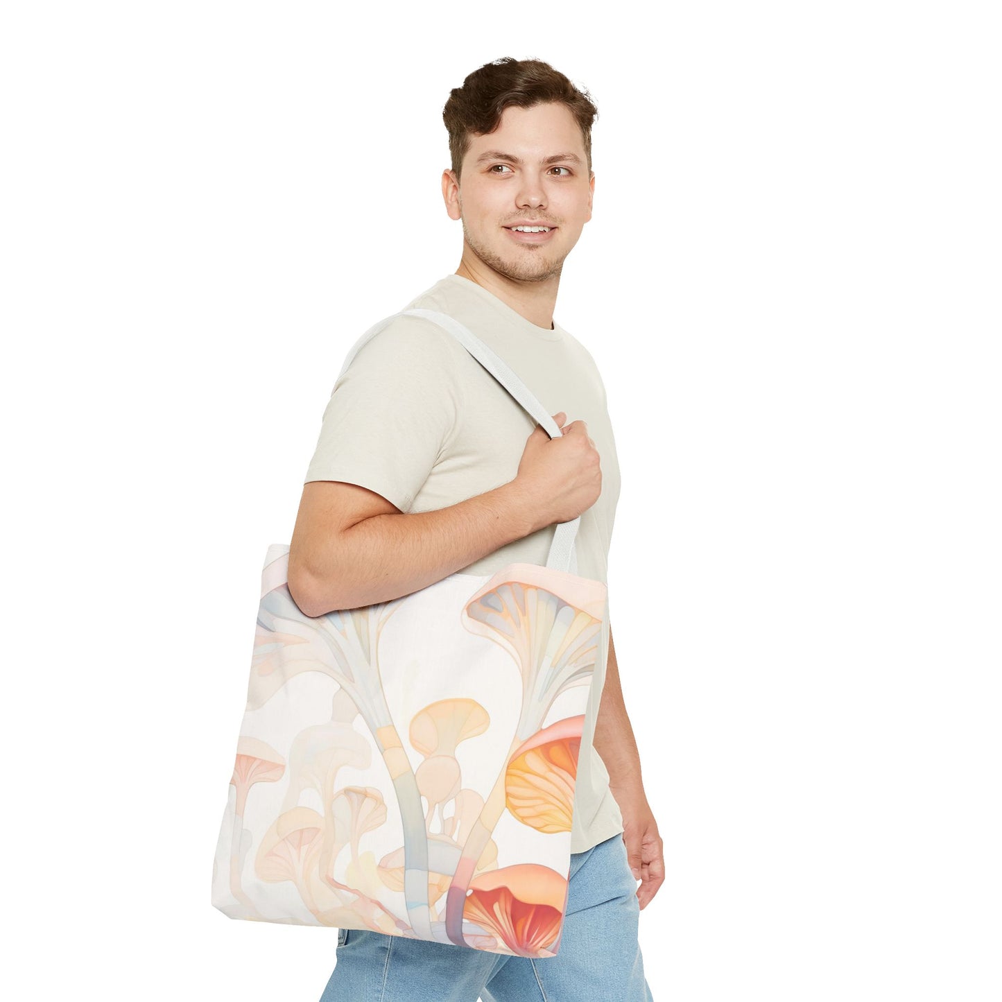 A person smiles while carrying a Groovy Rainbow Mushrooms Stained Glass Tote Bag, featuring a durable polyester build and colorful design. Wearing a light shirt and jeans, they stand against a plain white background.