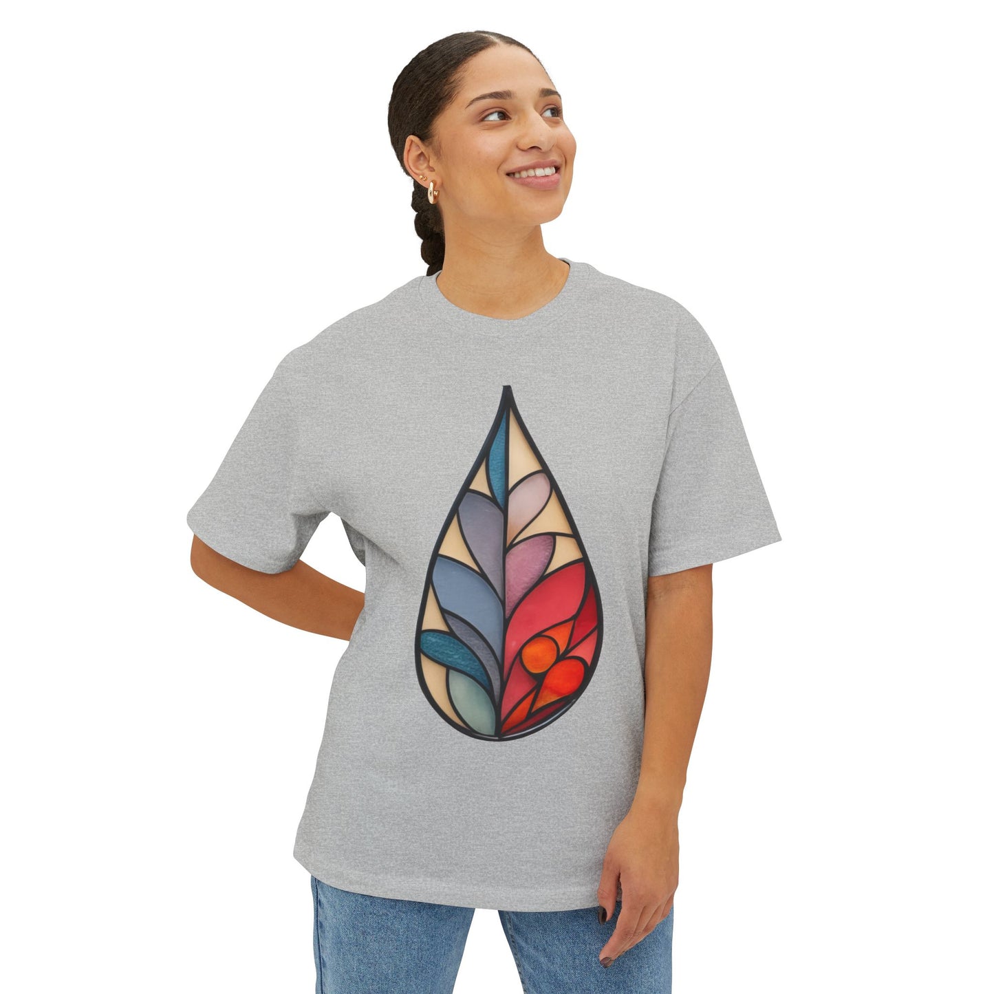 A person with dark hair pulled back is wearing a Stained Glass Botanical Raindrop Oversized Tee Shirt and blue jeans, smiling while looking to the side.